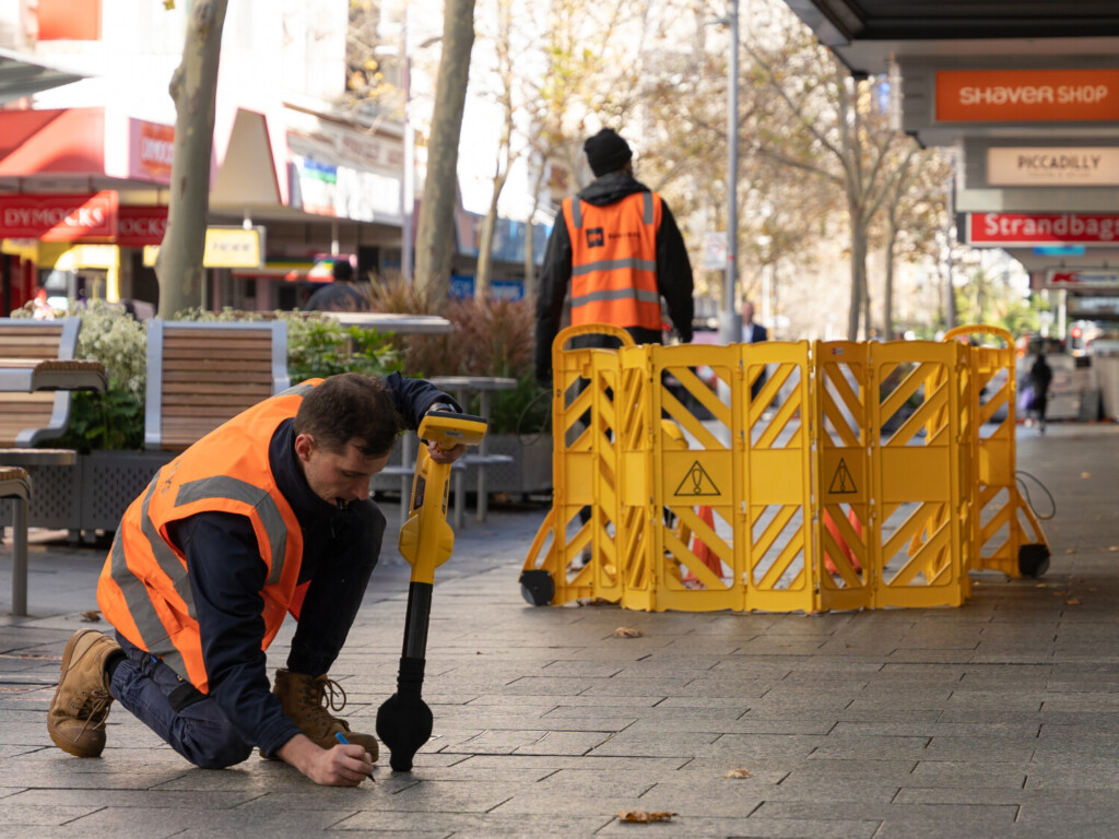 Engineer measuring underground utilities using mapping equipment.